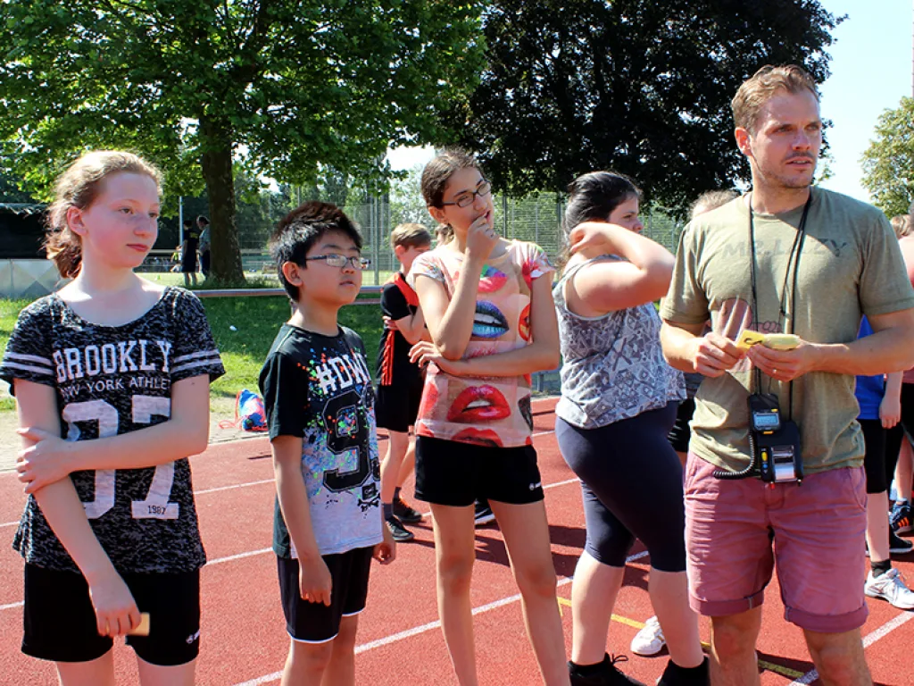Gruppe steht mit einer Aufsicht an der Bahn.
